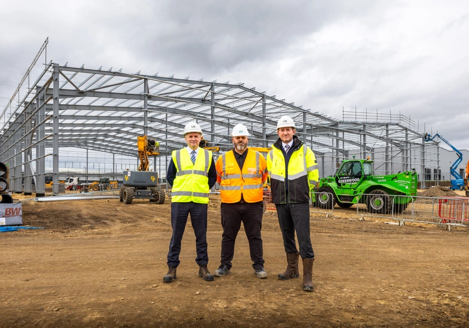 STP Construction and UK Land Estates representatives standing in front of warehouse under construction.